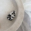 Detail of a french acetate hair clip with cow print pattern resting on a ceramic plate - Black and White Textured Triangle