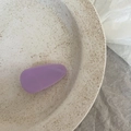 Macro view of purple acetate teardrop hair clip on a beige ceramic plate - Solid Purple Triangle