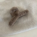 Large plush faux fur claw clip in soft coffee brown on cozy knit fabric background - Khaki