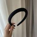 Nahaufnahme eines dicken schwarzen Wollstirnbandes in der Hand im Retro-Padded-Design - Schwarzer Schmaler Haarreif