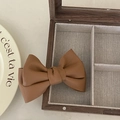 Elegant brown PU leather bow hair clip placed on a wooden jewelry box for styling - Bowknot Duckbill Clip / Caramel color