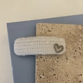 Dettaglio di un fermaglio per capelli in tweed crema con cuore in metallo e strass - Bianco
