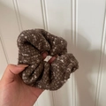 Detailopname van een zachte donkerbruine scrunchie met witte vezelaccenten voor de herfst - Koffie Haarelastiek