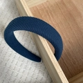 Detail van een donkerblauwe gewatteerde haarband van geweven stof op houten dienblad - Blauw Twill Textuur