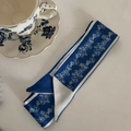 Dettaglio di un foulard in seta a fiori blu con tazza vintage su una superficie beige - Base Blu Motivo Floreale Bianco (4#)