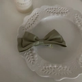 Dettaglio del fiocco in raso verde oliva con un design a clip a becco d'anatra in metallo - Clip Laterale con Fiocco Verde