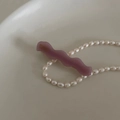 Nahaufnahme einer lila gewellten Acetat-Haarspange neben einer weißen Perlenkette - Lila Wellig Mit Buchstaben