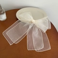 Detailed macro view of an oversized creamy white organza ribbon hair clip on a table - Large / Off White