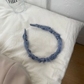 Detalle de diadema de satén plisado azul sobre fondo de lino blanco natural - Azul