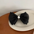 Dettaglio del fiocco nero elegante con perla centrale su un piatto di ceramica bianca - Nero Con Perla Rotonda