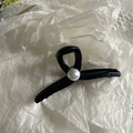 Detalle de la pinza para el pelo negra brillante con perla blanca en el centro - Estilo de Perlas Negras