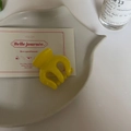 Détail d'une petite pince à cheveux en plastique jaune brillant sur une assiette déco - Pince Ronde Vert Jaune
