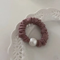 Elegante scrunchie in raso rosa con una grande perla bianca su un piatto di ceramica bianca - Color Tè al Latte