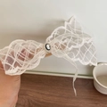 Dettaglio del fiocco in pizzo bianco con cammeo vintage e bordo di perle eleganti - Bianco