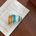 Detailansicht der wolkenförmigen Haarklammer aus Acetat mit bunten Glitzerstreifen auf Buch - Wolken-Haarklammer / Blau Gestreift (1#)