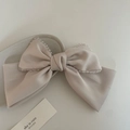 Eleganter cremefarbener Satin-Haarclip mit Perlenbesatz auf einem Dekoteller - Gebrochenes Weiß