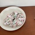 Gros plan sur un chouchou à imprimé tulipes roses et feuilles vertes sur une assiette blanche - Petit Chouchou Floral Rose Blanc