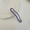 Detailed view of a wave-shaped purple and clear acrylic hair clip on a ceramic tray - Purple