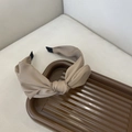 Detail van een Franse stijl knoop hoofdband in beige matte zijde op een dienblad - Koffie Geknoopte Hoofdband
