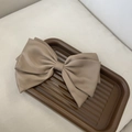 Detail view of a large mocha brown satin bow hair clip with tiered ribbon layers on a tray - Coffee Three-layer Bow Clip
