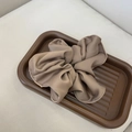Detailed view of a mocha satin scrunchie with hemmed edges in a brown tray - Coffee Scrunchie