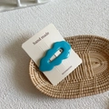 Detail of a bright blue wave-shaped acrylic hair clip on handmade accessory card - Blue