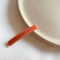 Detailed close-up of coral pink acrylic hair clip with a sparkling crystal stud - Orange Red