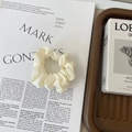 Detailed view of cream satin scrunchie placed on an artistic magazine with elegant props - Small / Off-white