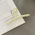 Molletta per capelli shark oversize in metallo verde chiaro opaco su un libro - Pinza a Molla Rettangolare Lunga / Bianco Sporco