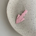 Pink matte metal hair clip with geometric hollow design on a beige ceramic plate - Pink