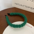 Detailed macro view of a green knitted twist headband placed on a white porcelain plate - Dark Green