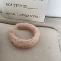 Close-up of soft pink faux rabbit fur headband with fluffy texture on beige fabric - Pink