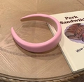 Detailed view of pink padded sponge headband with PU leather on a wooden table - Pink