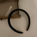 Dettaglio di cerchietto in pelle nera con fodera color cammello su cassetto di legno - Nero