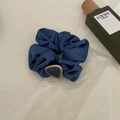 Detail eines dunkelblauen Satin-Haargummis mit einer goldenen Dreieck-Marmorschnalle - Blau