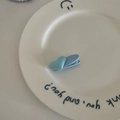 Détail de la pince à cheveux cœur bleu placée sur une assiette en céramique blanche - Petite Pince Bleu Clair
