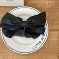 Elegant large black satin bow hair clip with a silky finish on a decorative plate - Black Large
