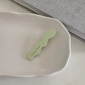 Dettaglio molletta per capelli verde chiaro a onde con testo francese su vassoio - Verde