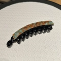 Detailed macro view of a marbled blue and brown banana hair clip on a white tray - Coffee Green Marble