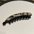 Nahaufnahme der Bananenspange aus Acetat mit weißem Leopardenmuster und schwarzen Kammzähnen - Helles Leopardenmuster
