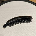 Detail view of acetate banana hair clip with tortoiseshell pattern and fine black comb teeth - Coffee Blue Marble
