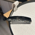 Close-up of black banana hair clip with shimmering colorful rhinestones in a tray - Green