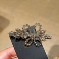 Dettaglio del fermaglio per capelli con cristalli grigi e finiture in lega dorata - Grigio