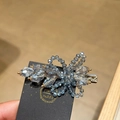 Dettaglio del fermaglio con fiori di cristallo blu fatto a mano e perline dorate su carta - Azzurro