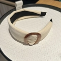 Detail of cream fabric headband featuring a retro brown tortoiseshell ring decoration - White