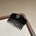 Detail of elegant black hair comb with white camellia flower on a dark wooden tray - Black