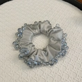 Elegant silver satin scrunchie with blue crystal beads on white texture tray - Light Blue