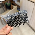 Primer plano de un peine para el cabello con cristales y brillantes pedrería sostenido a mano - Azul claro