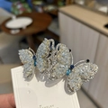 Exquisita pinza de mariposa con pedrería azul y blanca sobre una base plateada - Clip de Resorte de Mariposa de Cristal