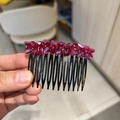 Detalle de una peineta de metal negro con brillantes cristales en color rojo rosado - Burdeos